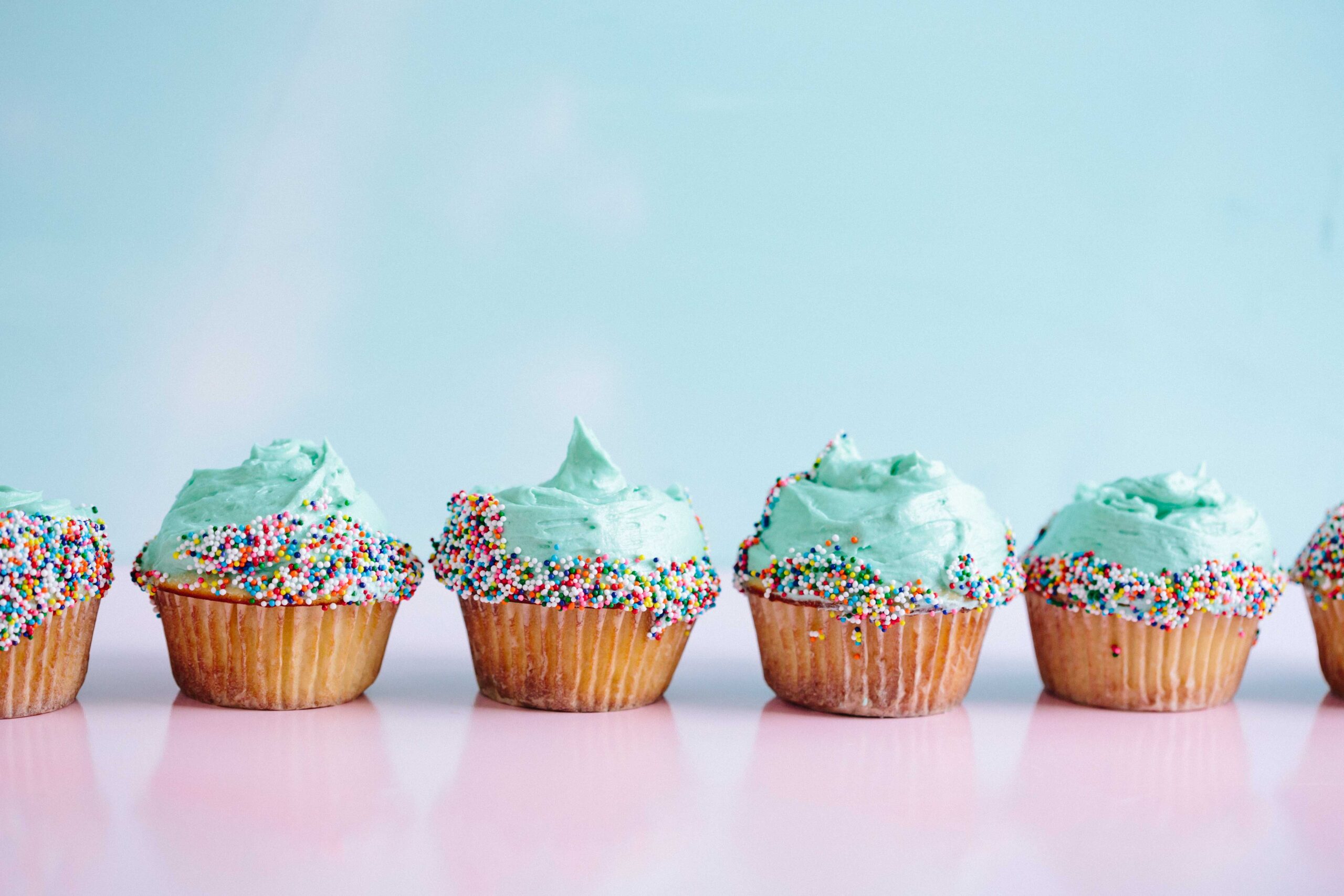 Row of cupcakes with blue icing and sprinkles