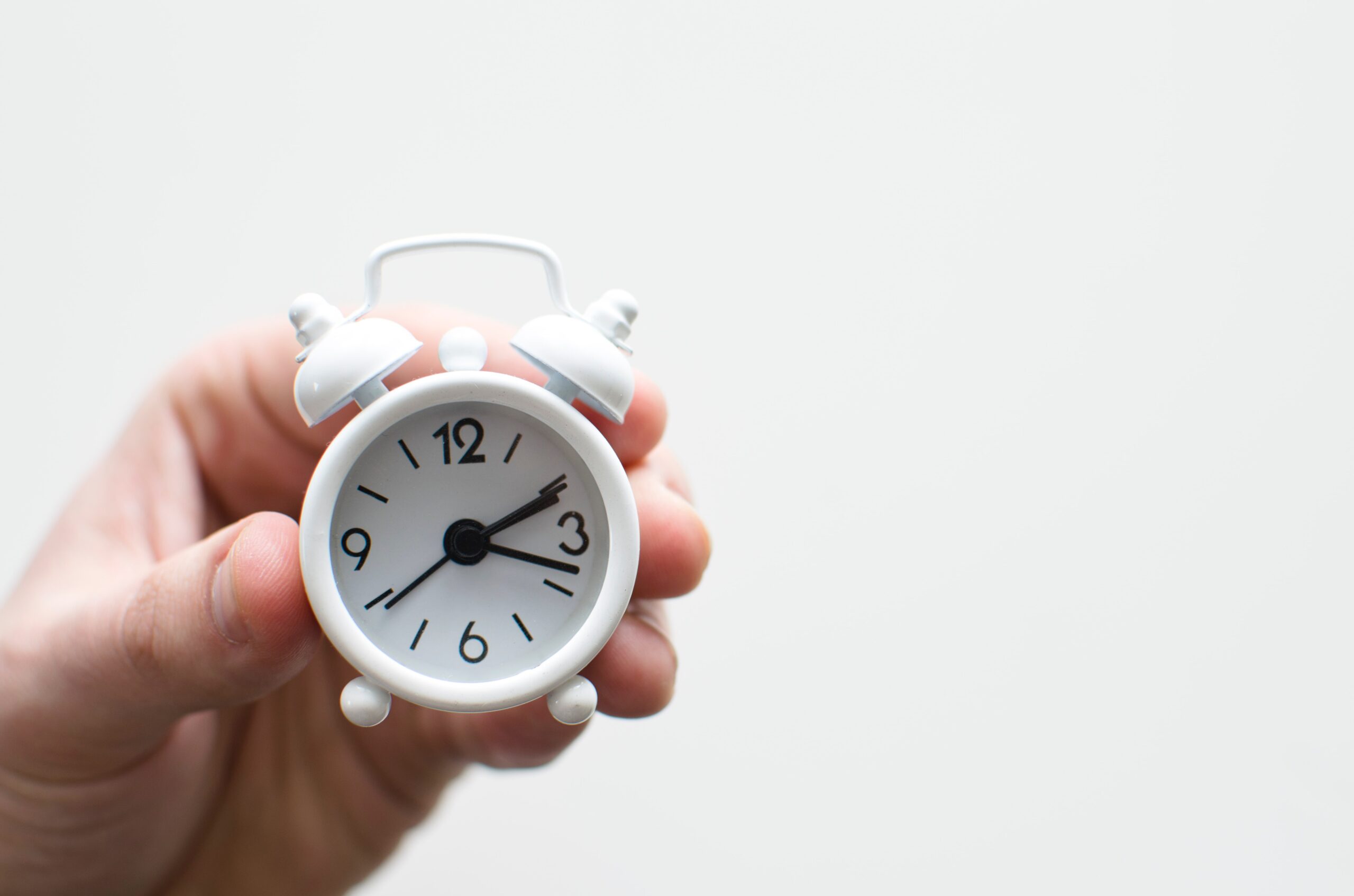Hand holding a small alarm clock