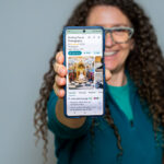 Jo Hailey holding a phone showing the Striking Places Google Business Profile with 5 stars from 131 reviews