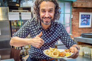 Restaurant owner giving thumbs up with plate of delicious foot