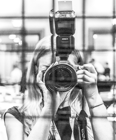 Carol Moir behind her canon camera with flash, lens facing