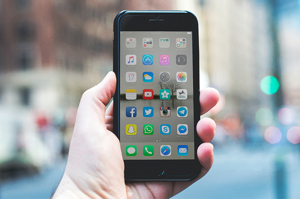 hand holding a phone showing social media icons