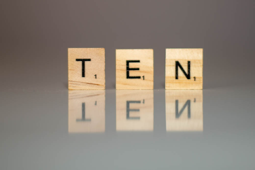 Scrabble letters, standing up on a surface, spelling out the word ten.